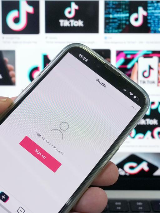 TikTok-App auf einem Smartphone vor Werbe-Screens in Sydney, Australien