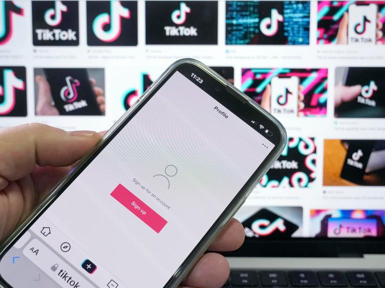 TikTok-App auf einem Smartphone vor Werbe-Screens in Sydney, Australien