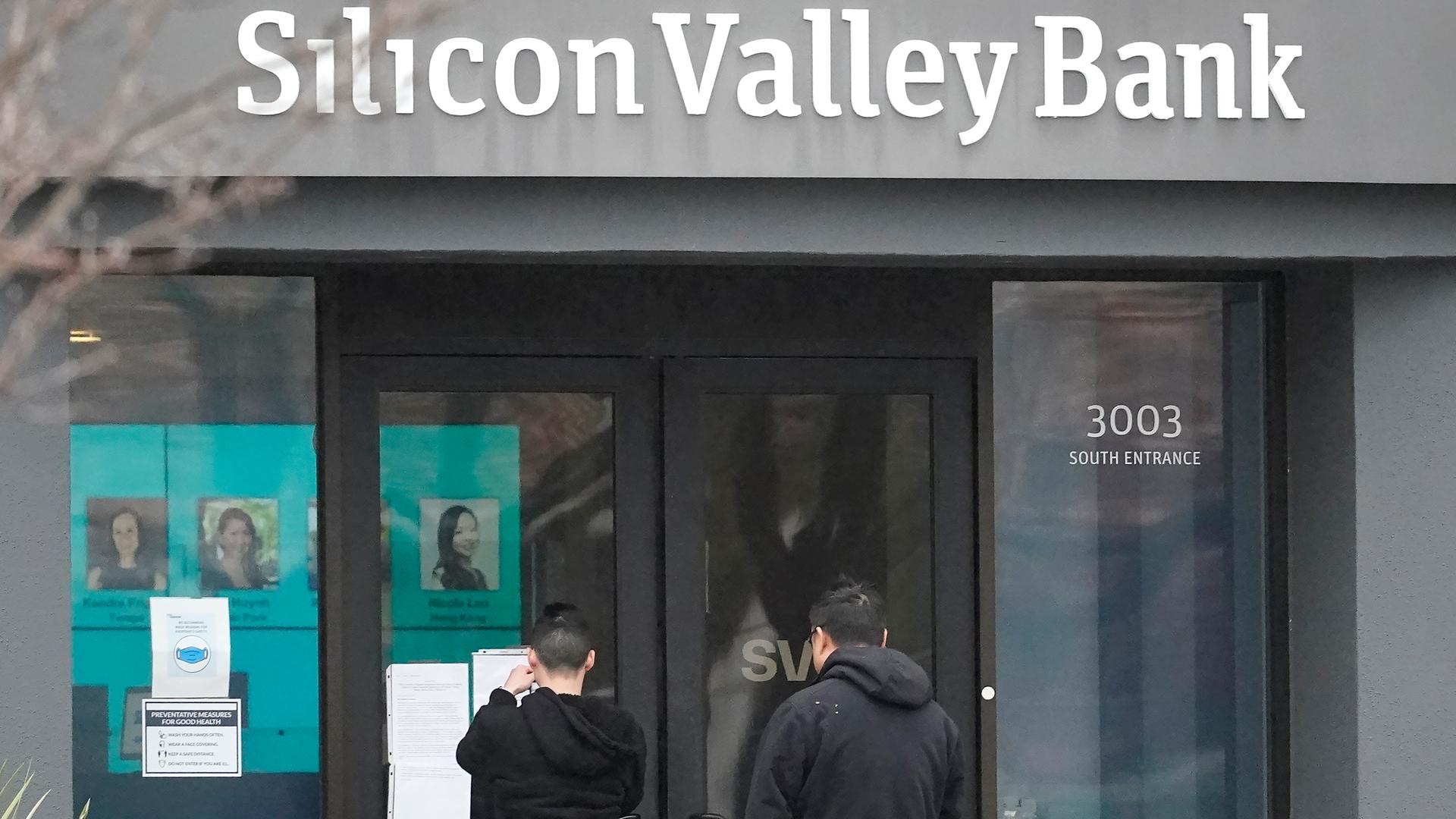 Menschen schauen auf Schilder vor dem Eingang der Silicon Valley Bank in Santa Clara, Kalifornien