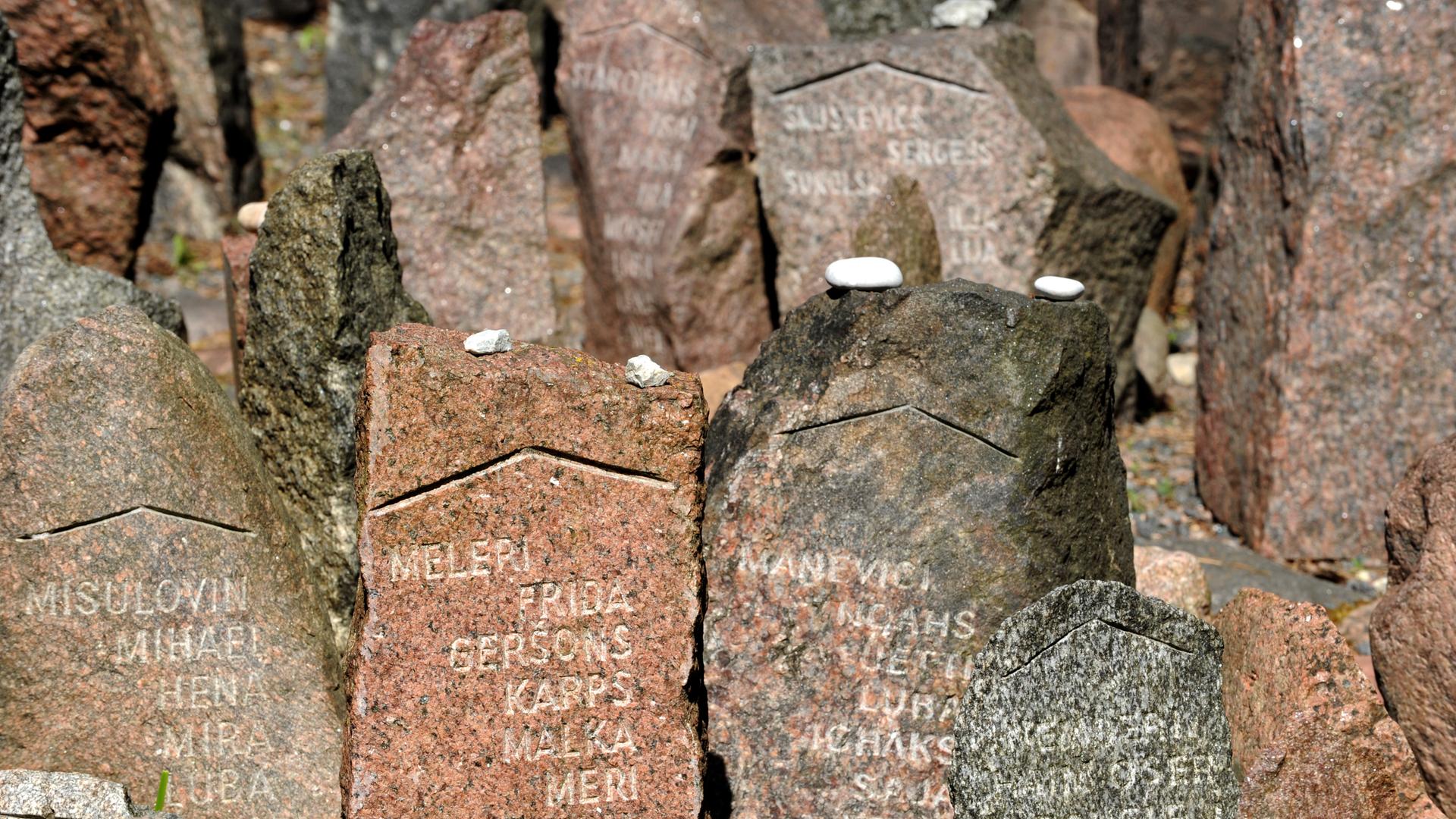 Mit Namen versehene Gedenksteine im Wald von Rumbula nahe Riga. An dieser Stelle erschossen deutsche Truppen 1941 mehr als 27.000 Jüdinnen und Juden Mit Namen versehene Gedenksteine im Wald von Rumbula nahe Riga. An dieser Stelle erschossen deutsche Truppen 1941 mehr als 27.000 Jüdinnen und Juden