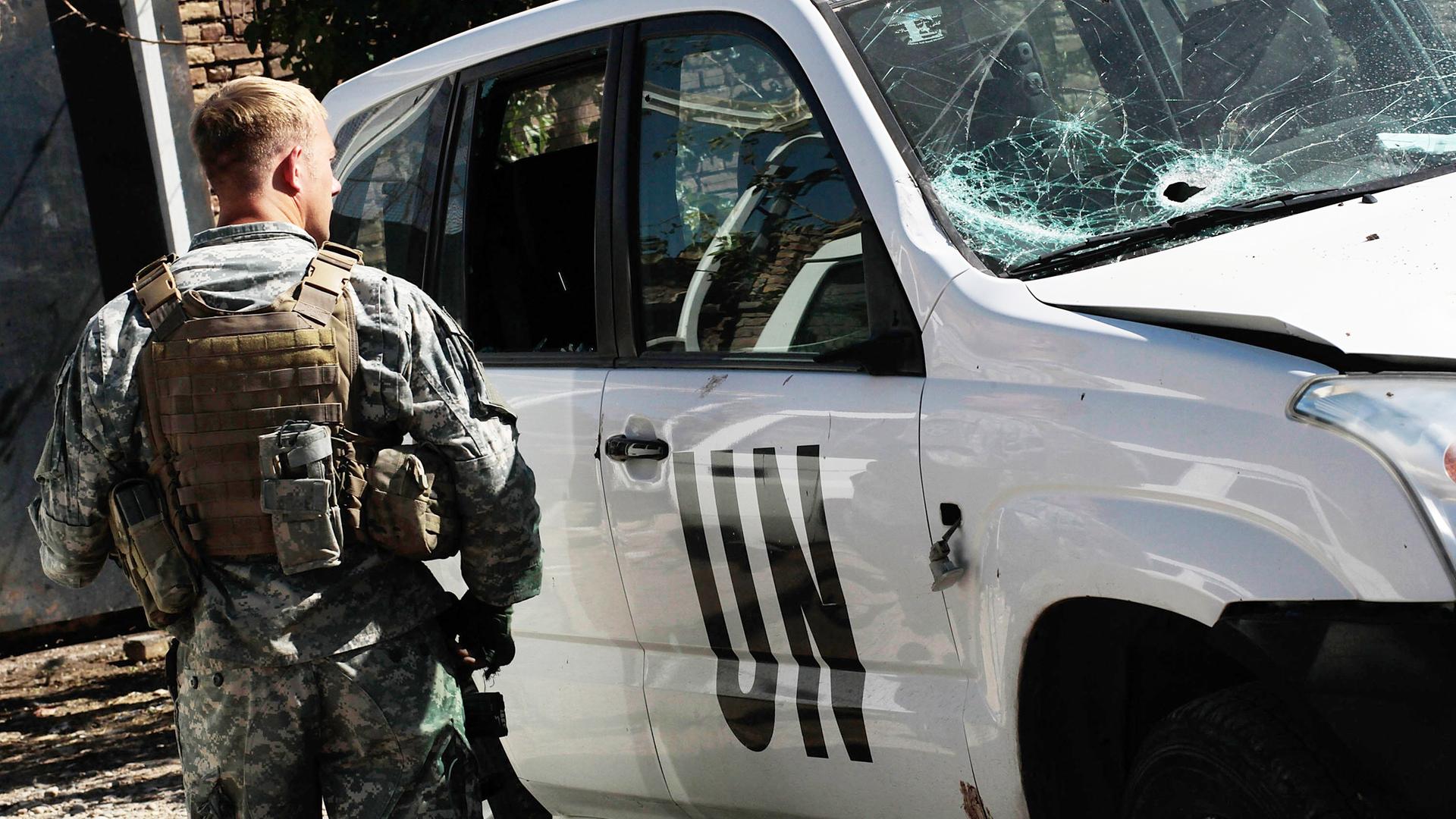 Ein amerikanischer UN Soldat steht neben einem Auto mit zerstörter Windschutzscheibe in Herat, Afghanistan, 2010. Ein amerikanischer UN Soldat steht neben einem Auto mit zerstörter Windschutzscheibe in Herat, Afghanistan, 2010.