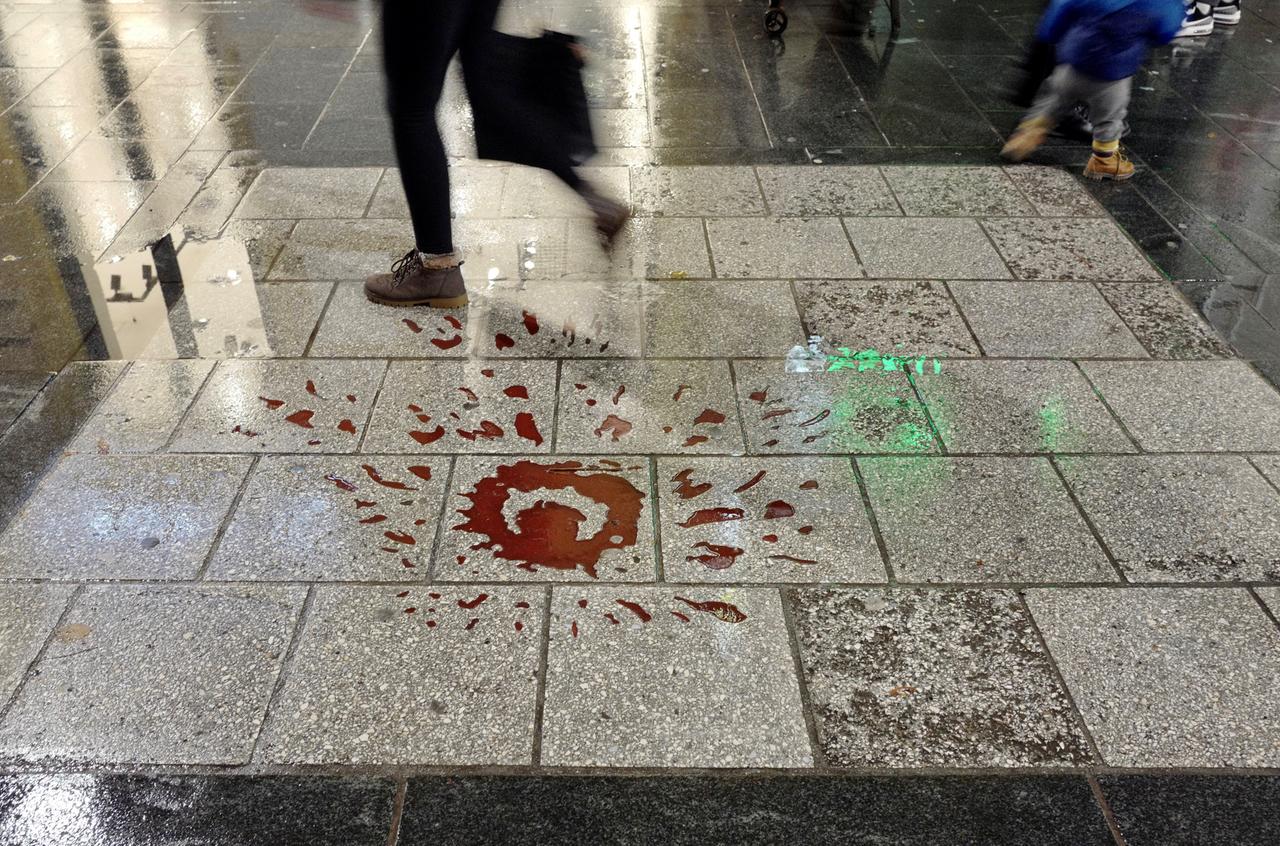 Das Bildnis einer roten Rose, deren Blütenblätter an Blutspritzer erinnern, ist auf Gehwegplatten gezeichnet. Das Bildnis einer roten Rose, deren Blütenblätter an Blutspritzer erinnern, ist auf Gehwegplatten gezeichnet.