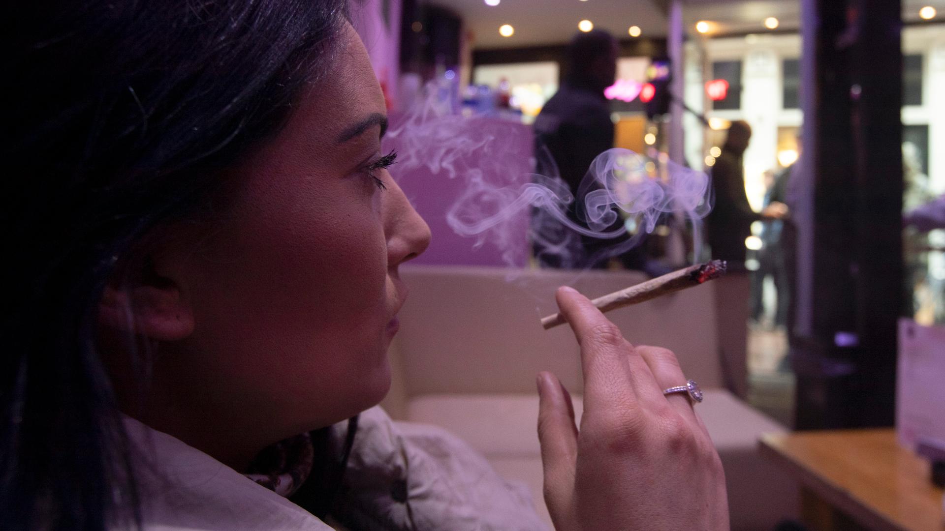 Eine Frau sitz in Amsterdam in einem Coffeeshop und raucht einen Joint. Eine Frau sitz in Amsterdam in einem Coffeeshop und raucht einen Joint.