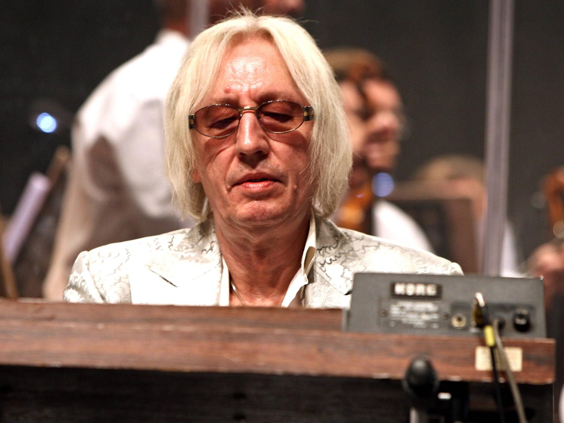 Der Keyborder Ed Swillms trägt einen weißen Anzug und spielt einen Korg-Synthesizer.