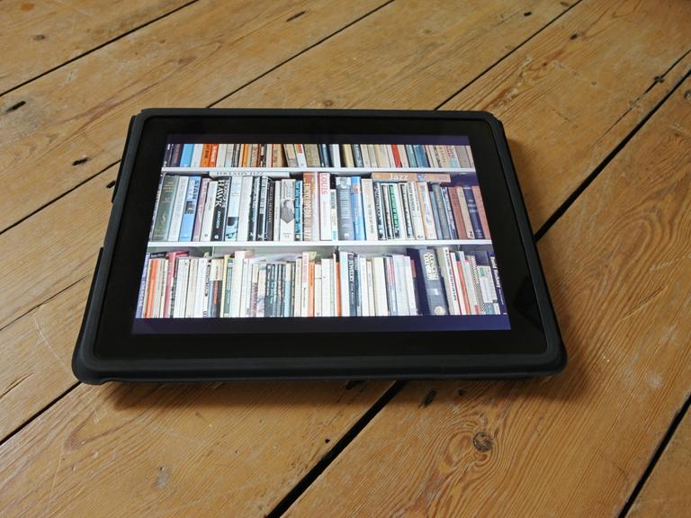 Auf einem Tablet wird ein ganzes Bücherregal dargestellt.