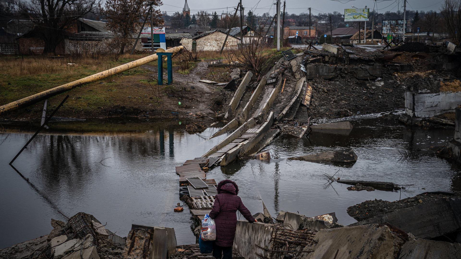 Eine Frau überquert eine zerstörte Brücke in Bachmut in der Region Donezk