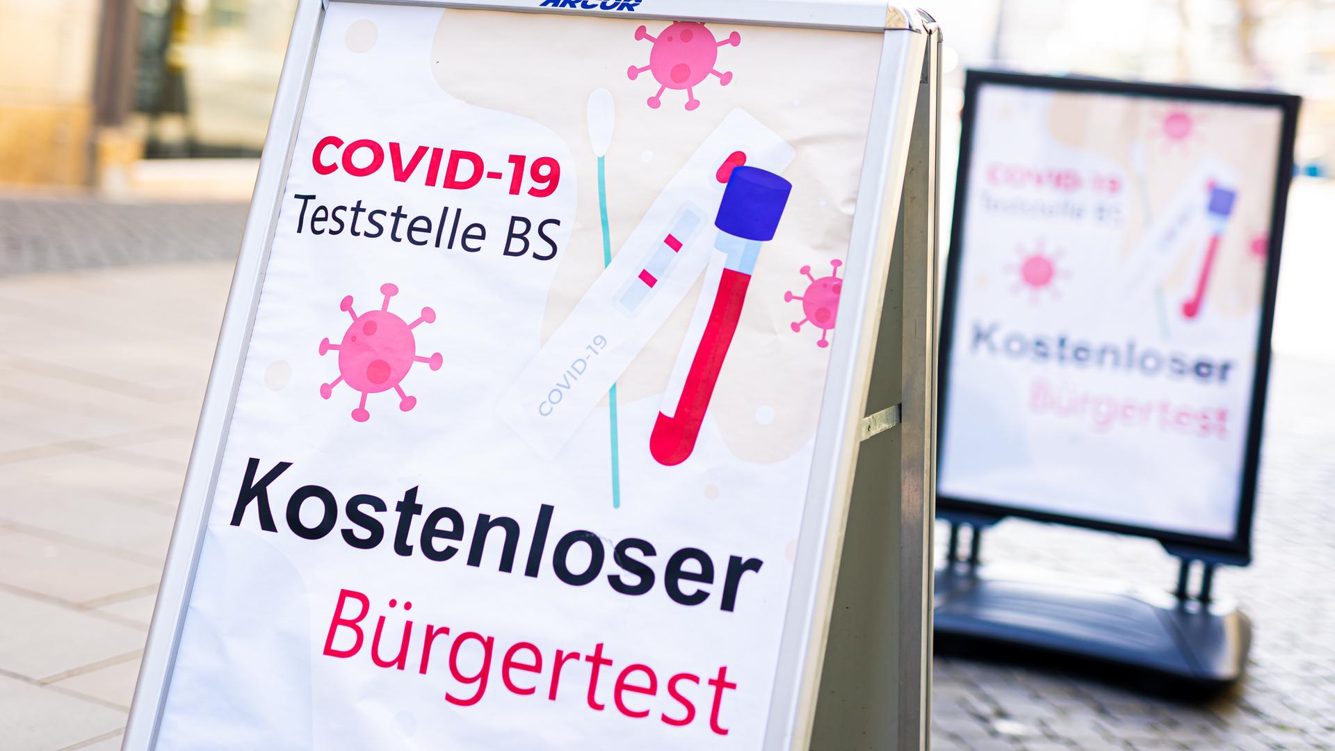 Ein kostenloser Bürgertest auf das Coronavirus wird auf einem Aufsteller in der Innenstadt beworben. Ein kostenloser Bürgertest auf das Coronavirus wird auf einem Aufsteller in der Innenstadt beworben.