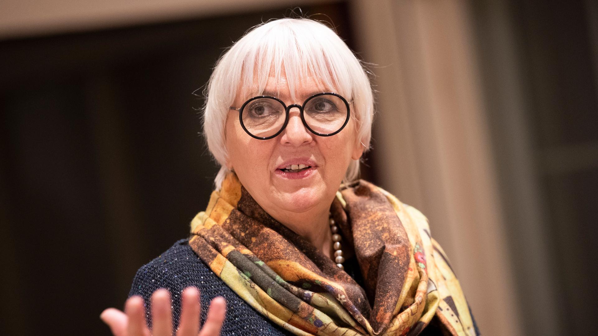 Kulturstaatsministerin Claudia Roth mit schwarzer Brille und buntem Tuch gestikuliert in die Kamera. Kulturstaatsministerin Claudia Roth mit schwarzer Brille und buntem Tuch gestikuliert in die Kamera.