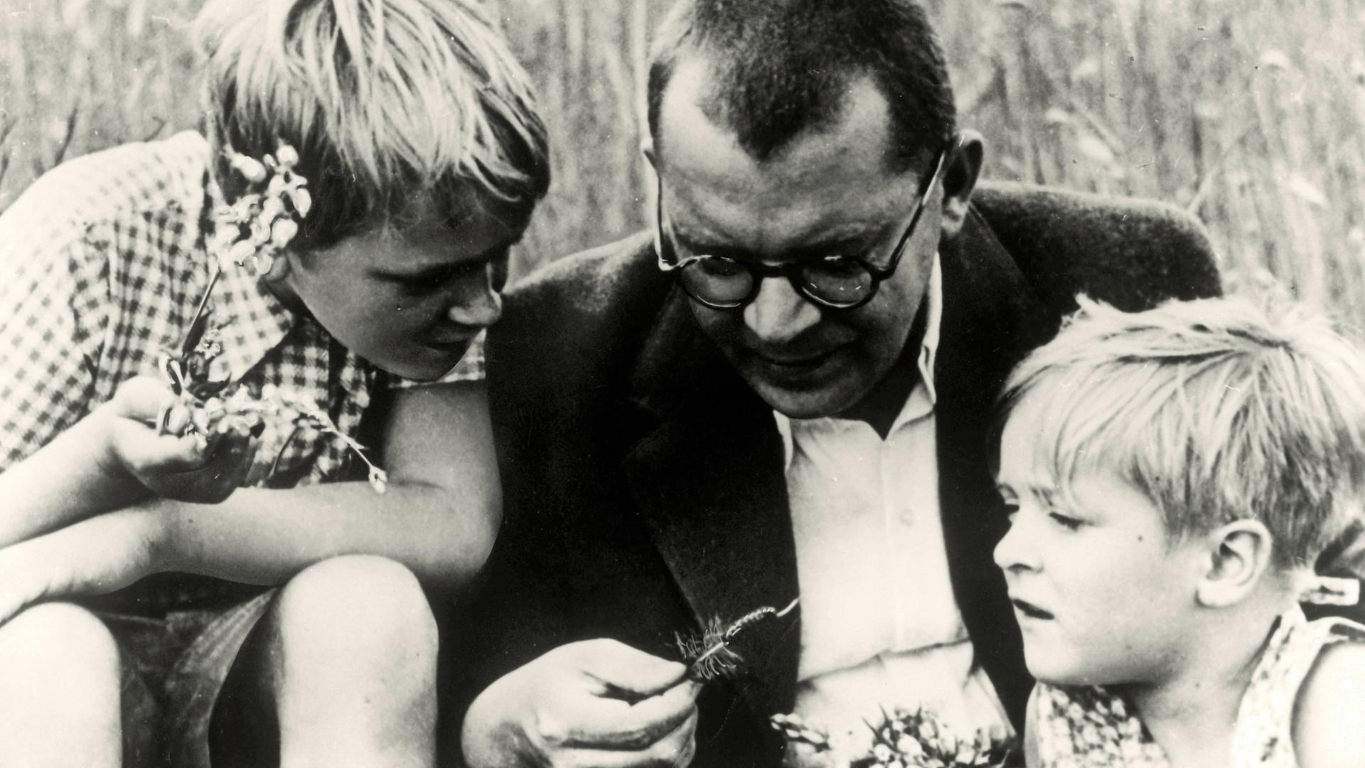Hans Fallada sitzt mit seinen Kindern Ulli und Lore in Carwitz im heutigen Mecklenburg-Vorpommern auf einer Wiese und schaut sich eine Raupe mit ihnen an. Hans Fallada sitzt mit seinen Kindern Ulli und Lore in Carwitz im heutigen Mecklenburg-Vorpommern auf einer Wiese und schaut sich eine Raupe mit ihnen an.