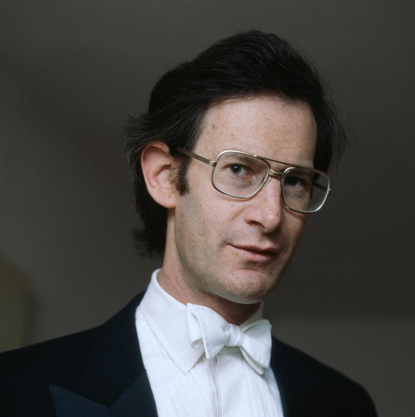 Der jüngere Dirigent John Eliot Gardiner blickt mit großer Brille und dunklem Haar in die Kamera. Der jüngere Dirigent John Eliot Gardiner blickt mit großer Brille und dunklem Haar in die Kamera.