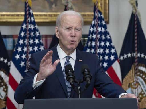 US-Präsident Joe Biden macht eine beschwichtige Geste an einem Rednerpult, hinter ihm die amerikanische Flagge.