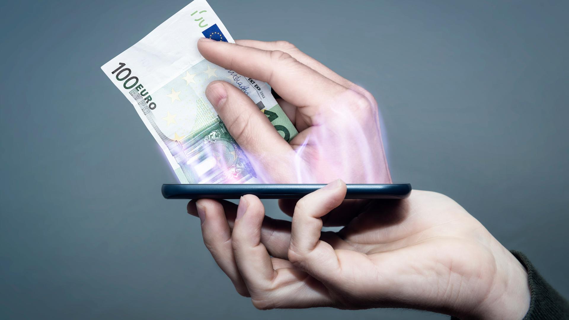 Eine Hand hält ein Smartphone, während eine andere Hand aus dem Display heraus ragt und bezahlt. Eine Hand hält ein Smartphone, während eine andere Hand aus dem Display heraus ragt und bezahlt.