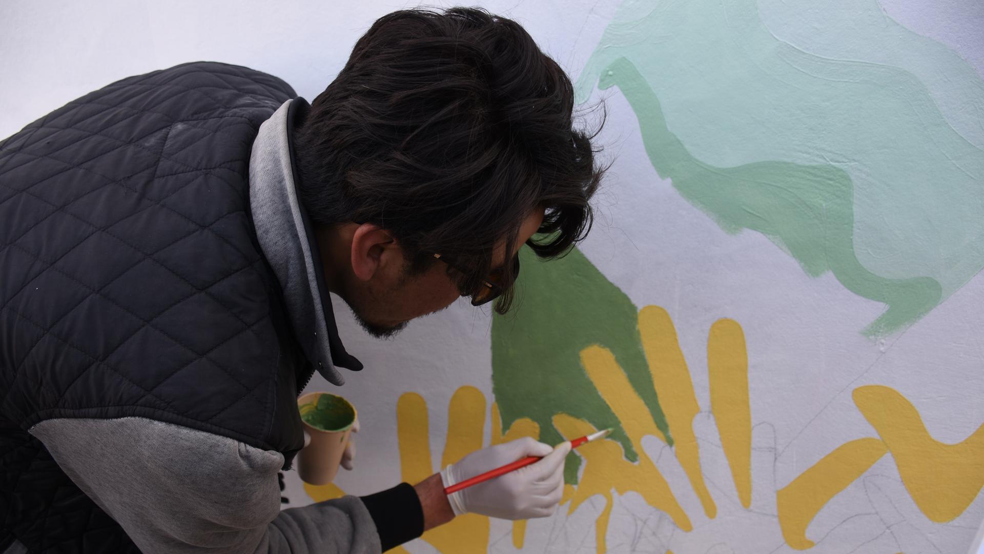 Ein afghanischer Künstler malt mit dem Pinsel ein Wandgemälde. 