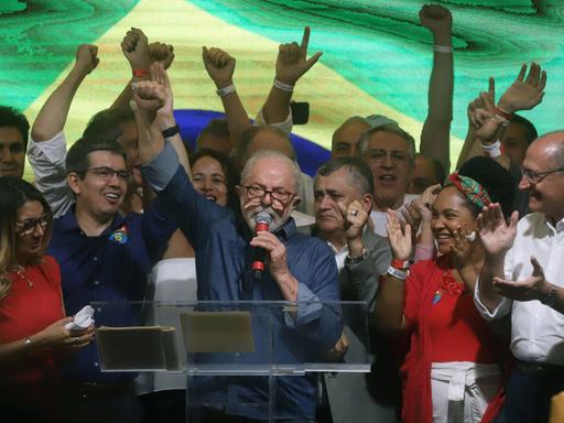 Lula da Silva steht inmitten jubelnder Anhänger, spricht in ein Mikrofon und hebt die rechte Faust.