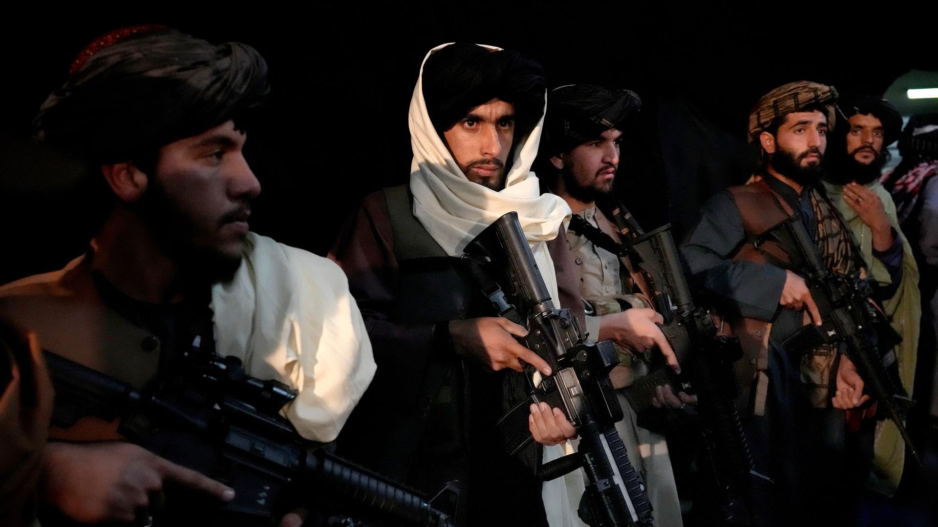 Mit Maschinengewehren bewaffnete Talibankämpfer stehen nebeneinander in einer Reihe.