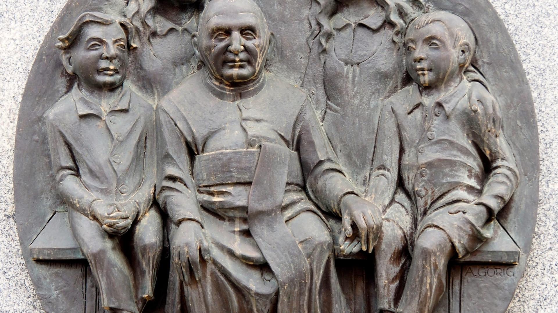 Relief des Ordensgründer Dominikus Ringeisen und betreute Kinder. Relief des Ordensgründer Dominikus Ringeisen und betreute Kinder.