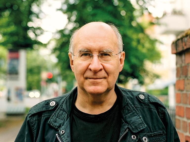 Der Autor Peter Wensierski, ein Mann mit kahlem Kopf und Brille schaut ernst.