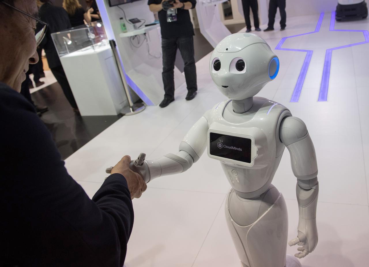 Ein kleiner weißer humnaoider Roboter gibt einem Menschen die Hand. Ein kleiner weißer humnaoider Roboter gibt einem Menschen die Hand.