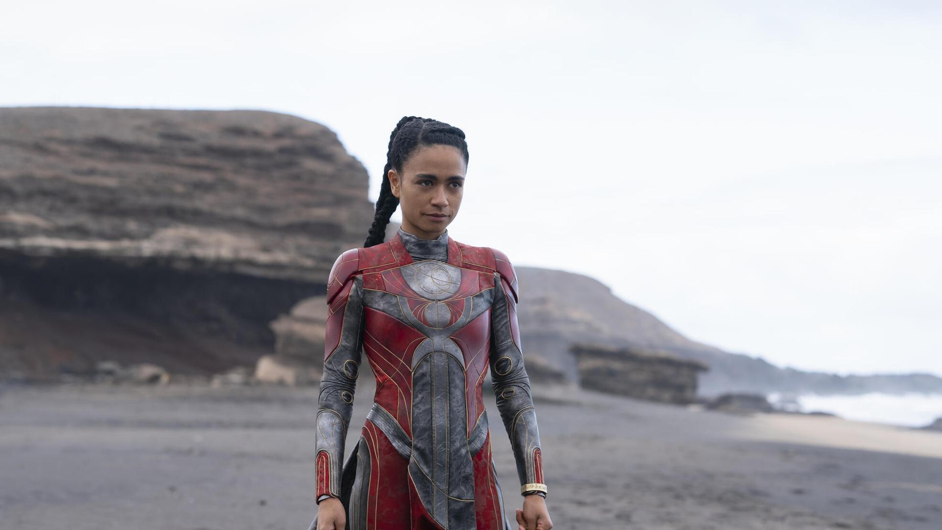 Im Still aus "Eternals" steht die Figur Makkari in einem roten Anzug am Strand. Im Still aus "Eternals" steht die Figur Makkari in einem roten Anzug am Strand.