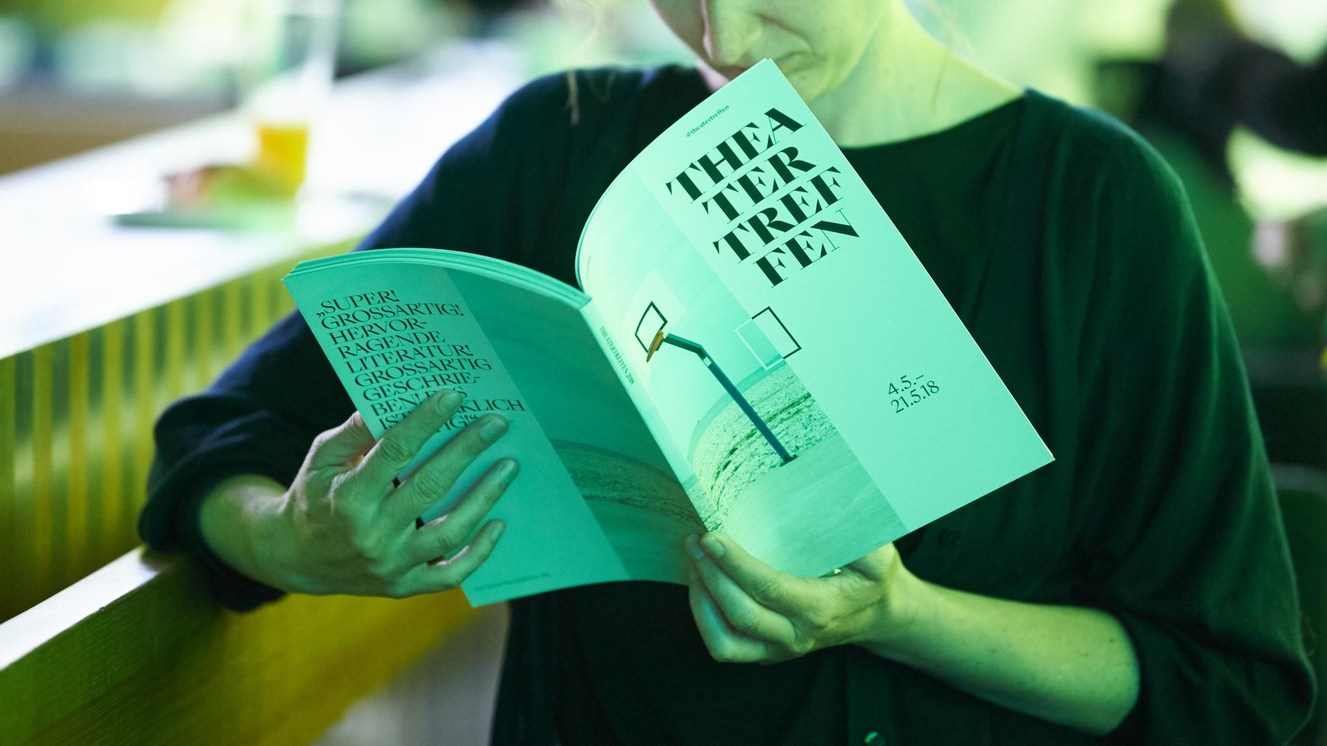 Eine Frau liest im Programm zum Theatertreffen. Eine Frau liest im Programm zum Theatertreffen.