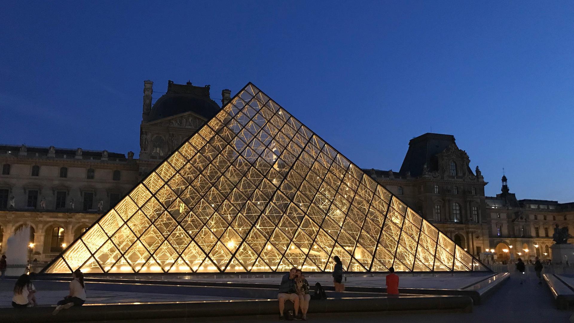 Die Glaspyramide im Innenhof des Louvre beleuchtet bei Nacht.