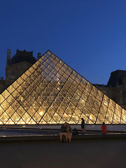Die Glaspyramide im Innenhof des Louvre beleuchtet bei Nacht.