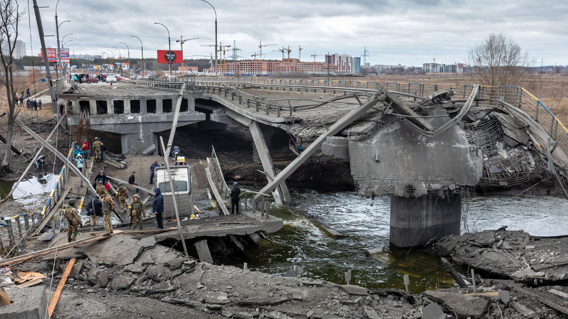 Krieg in der Ukraine: Bei der Evakuierung von Irpin überqueren flüchtende Menschen eine zerstörte Brücke. Krieg in der Ukraine: Bei der Evakuierung von Irpin überqueren flüchtende Menschen eine zerstörte Brücke.