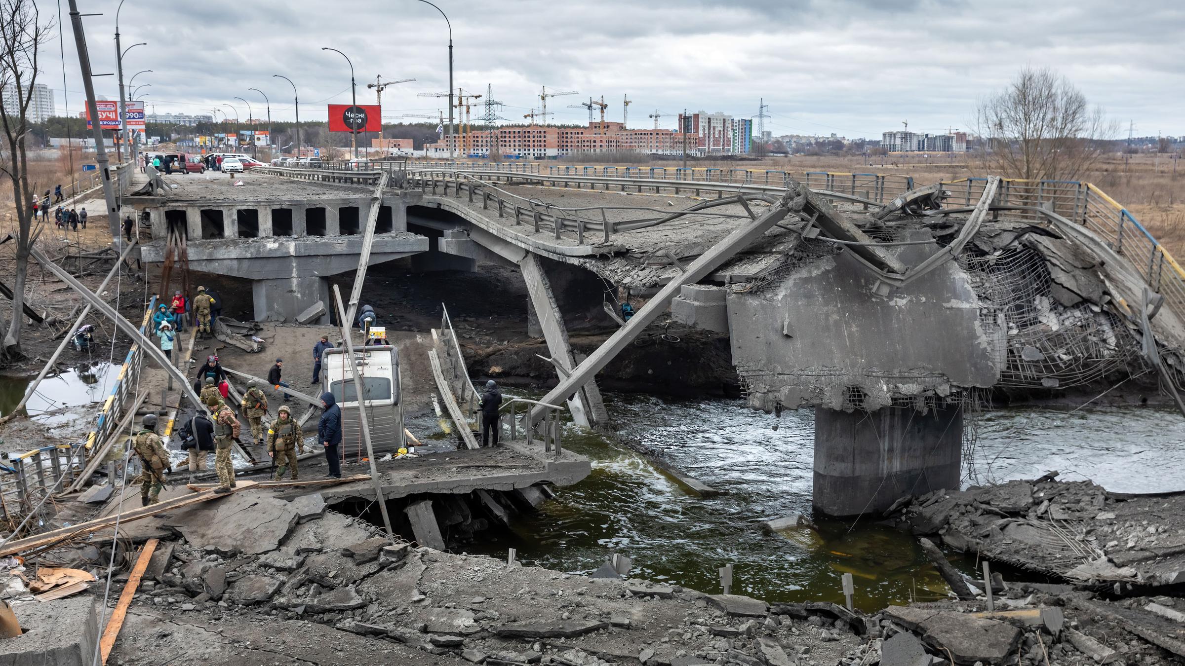 Krieg in der Ukraine: Bei der Evakuierung von Irpin überqueren flüchtende Menschen eine zerstörte Brücke.