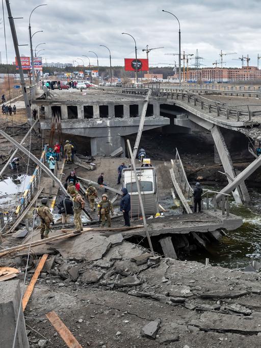 Krieg in der Ukraine: Bei der Evakuierung von Irpin überqueren flüchtende Menschen eine zerstörte Brücke.