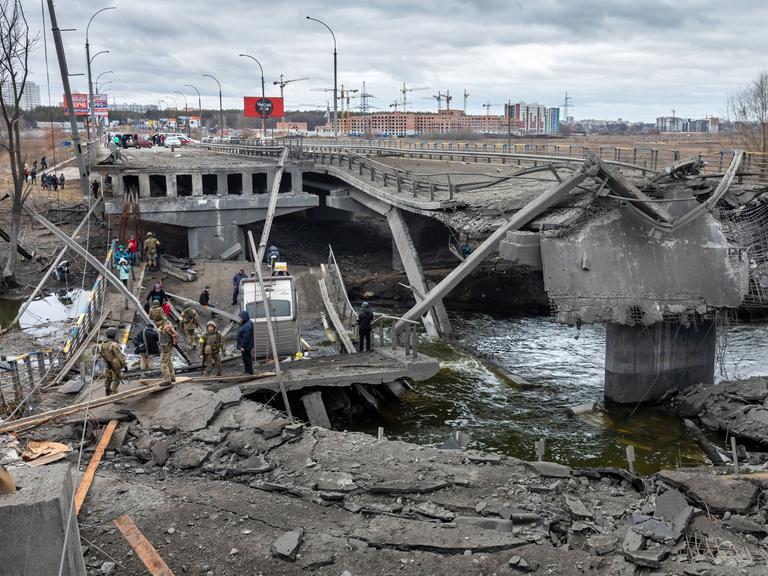 Krieg in der Ukraine: Bei der Evakuierung von Irpin überqueren flüchtende Menschen eine zerstörte Brücke.