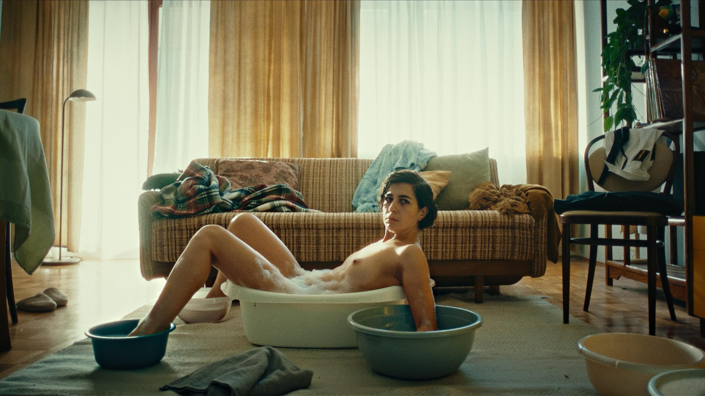 Eine Frau liegt nackt vor einer Couch badet Hände und Füße in Schüsseln...</p>

                        <a href=