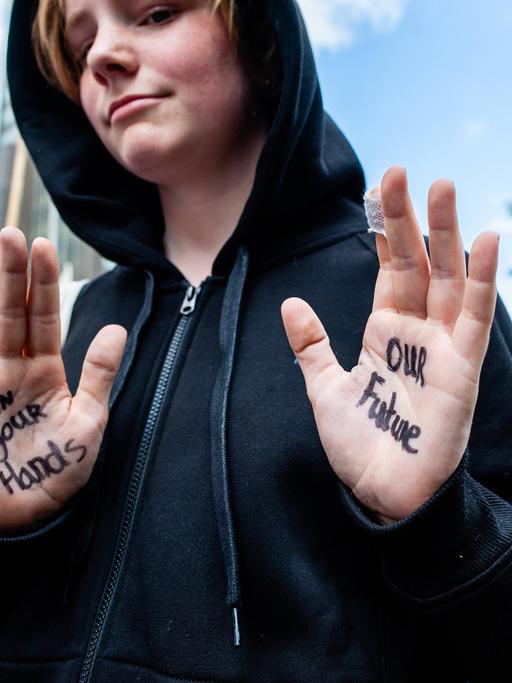Ein junger Demonstrant zeigt seine Hände, auf denen geschrieben steht: "In your Hands - Our Future", zu Deutsch: "In deinen Händen - unsere Zukunft"
