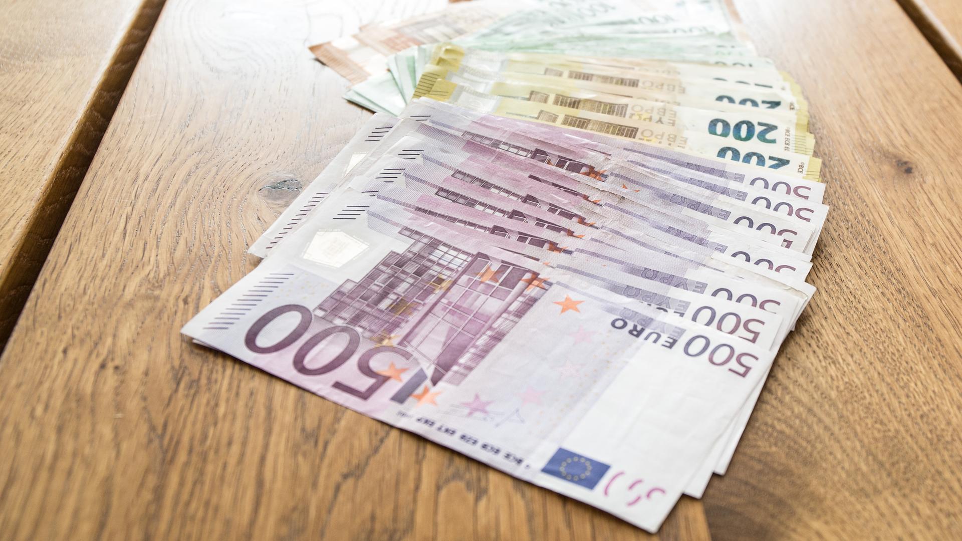 Mehrere tausend Euros in Bargeld mit den Werten von 500 Euro, 200 Euro, 100 Euro und 50 Euro liegen aufgereiht auf einem Tisch Mehrere tausend Euros in Bargeld mit den Werten von 500 Euro, 200 Euro, 100 Euro und 50 Euro liegen aufgereiht auf einem Tisch
