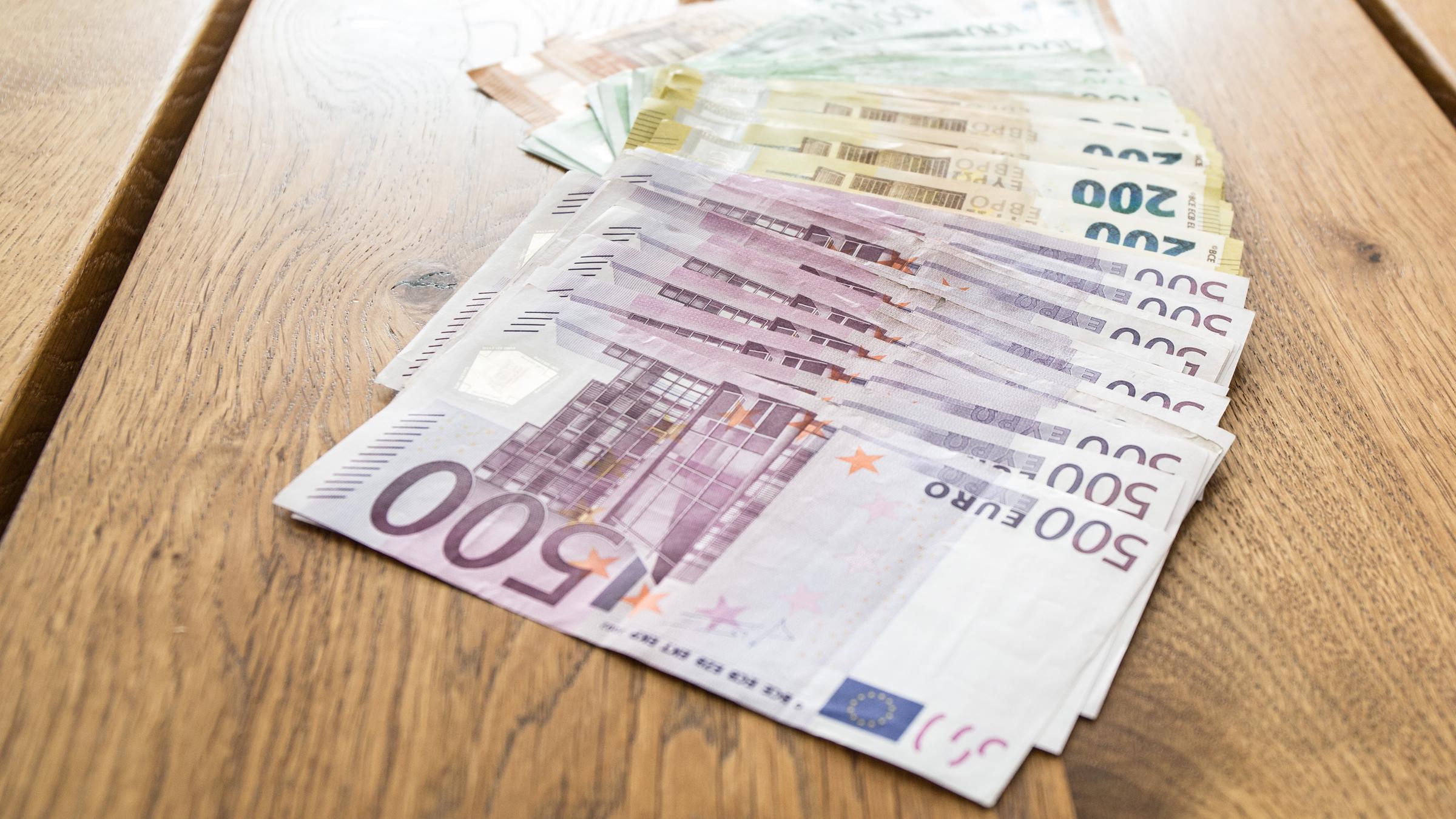 Mehrere tausend Euros in Bargeld mit den Werten von 500 Euro, 200 Euro, 100 Euro und 50 Euro liegen aufgereiht auf einem Tisch Mehrere tausend Euros in Bargeld mit den Werten von 500 Euro, 200 Euro, 100 Euro und 50 Euro liegen aufgereiht auf einem Tisch