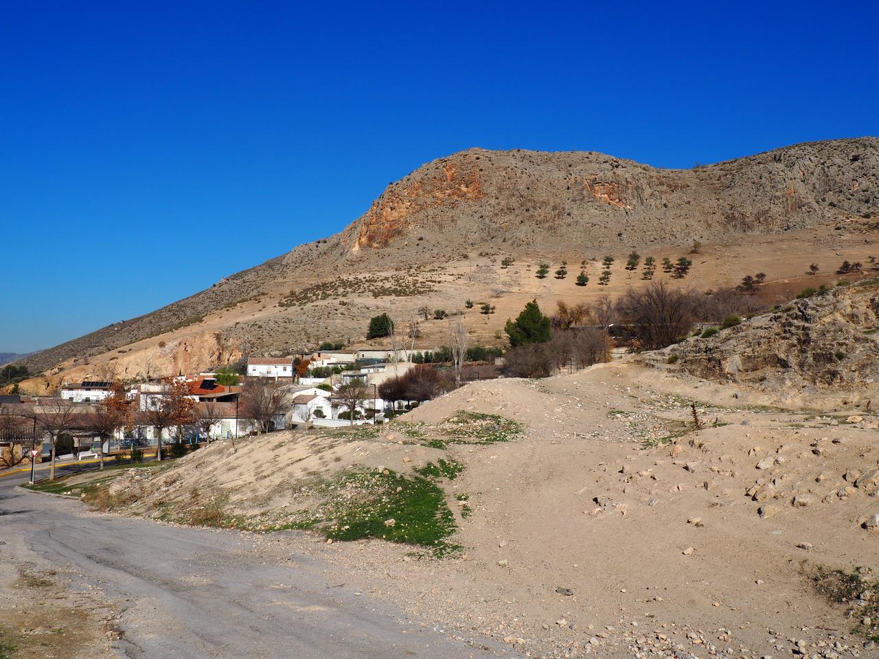 Am Fuß eines kahlen Berges inmitten einer kargen Landschaft liegt ein kleines Dorf mit kleinen flachen weißen Häuschen. Am Fuß eines kahlen Berges inmitten einer kargen Landschaft liegt ein kleines Dorf mit kleinen flachen weißen Häuschen.
