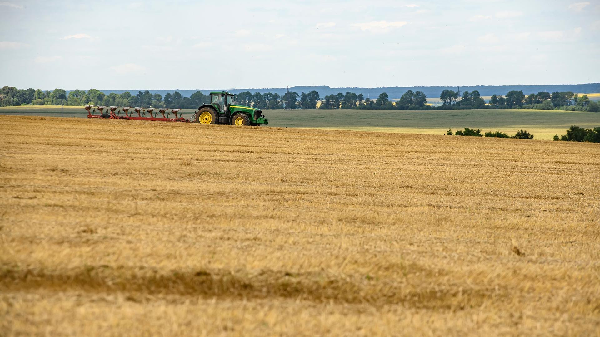 Ein Traktor fährt über Felder mit verschiedenem Getreide in der Ukraine. Ein Traktor fährt über Felder mit verschiedenem Getreide in der Ukraine.