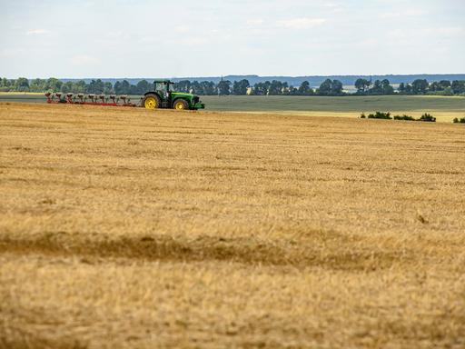 Ein Traktor fährt über Felder mit verschiedenem Getreide in der Ukraine.
