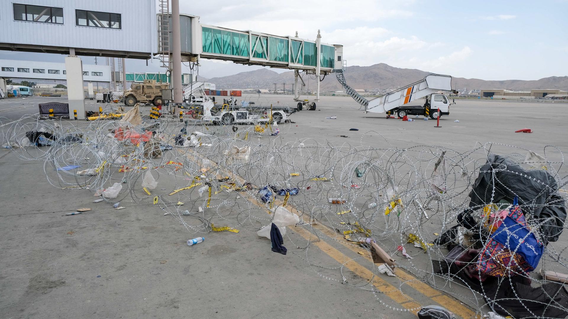 Der Flughafen in Kabul, Afghanistan. Gepäckstücke und Müll hängen in Stacheldrahtzäunen, die die Taliban gezogen haben. Der Flughafen in Kabul, Afghanistan. Gepäckstücke und Müll hängen in Stacheldrahtzäunen, die die Taliban gezogen haben.