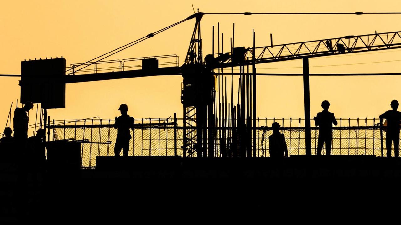 Silhouette von Arbeitern auf einer Baustelle. Silhouette von Arbeitern auf einer Baustelle.