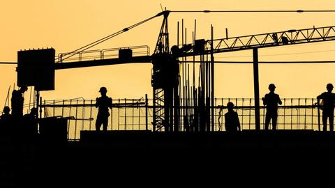 Silhouette von Arbeitern auf einer Baustelle.