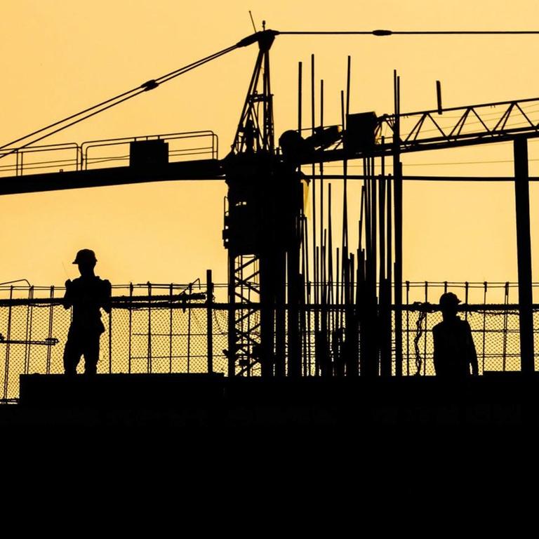 Silhouette von Arbeitern auf einer Baustelle.