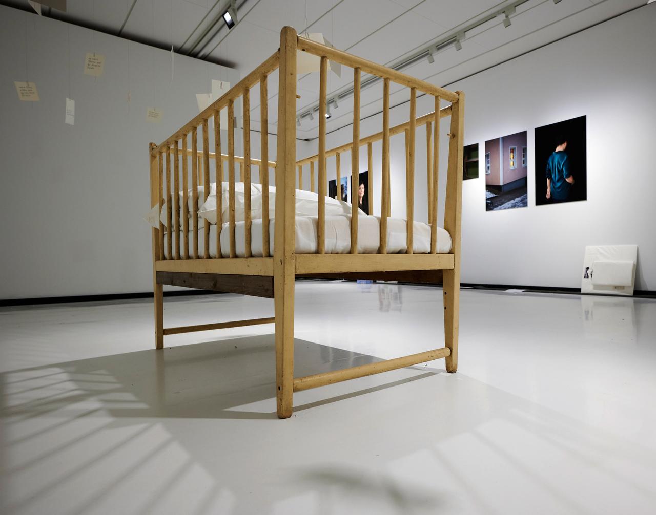 In der Ausstellung «Wochenkrippen in der DDR» steht ein hölzernes Gitterbettchen im Zentrum eines Raumes.