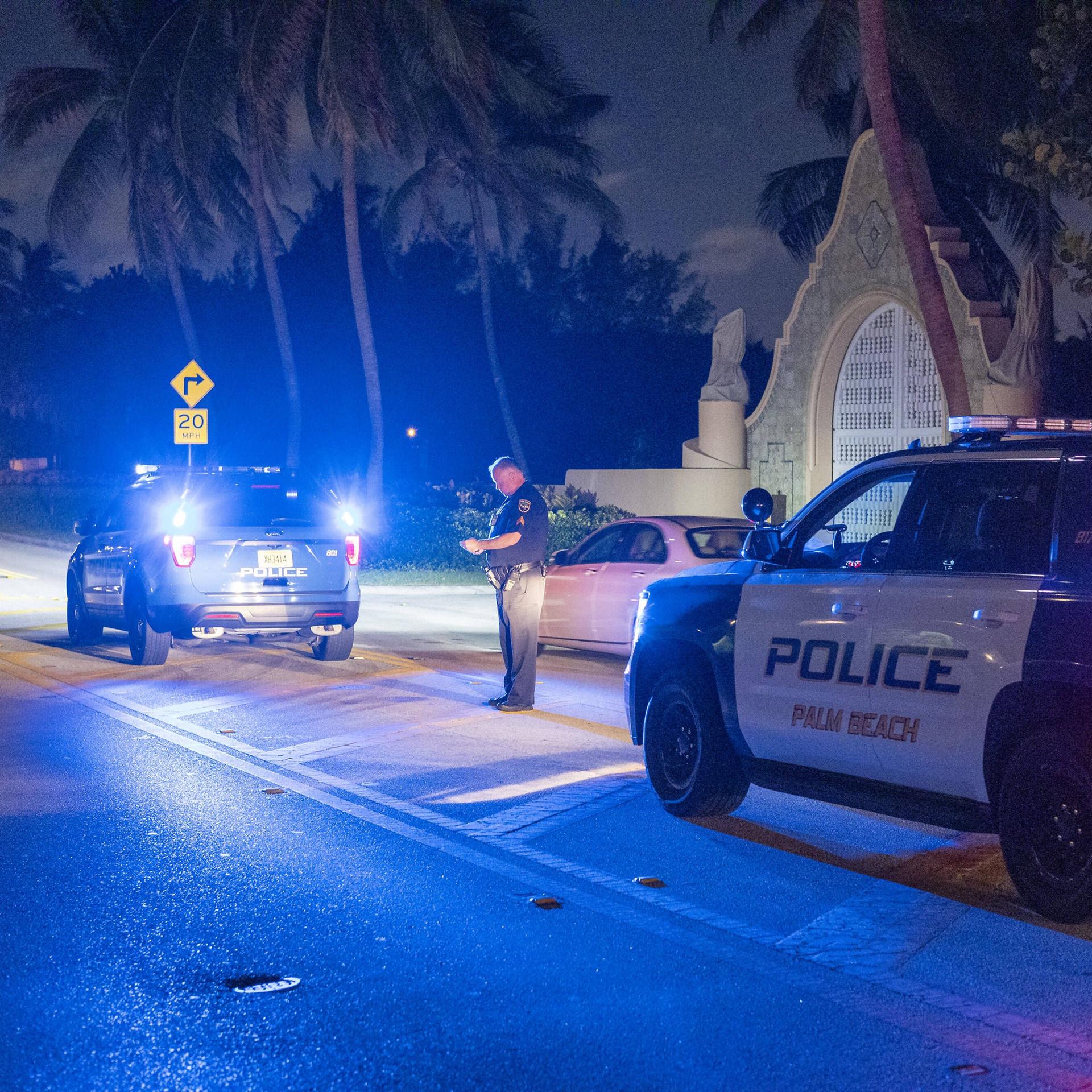 Zwei Polizeiwagen stehen in der Nacht vor dem Anwesen Mar-A-Lago von Donald Trump in Florida.