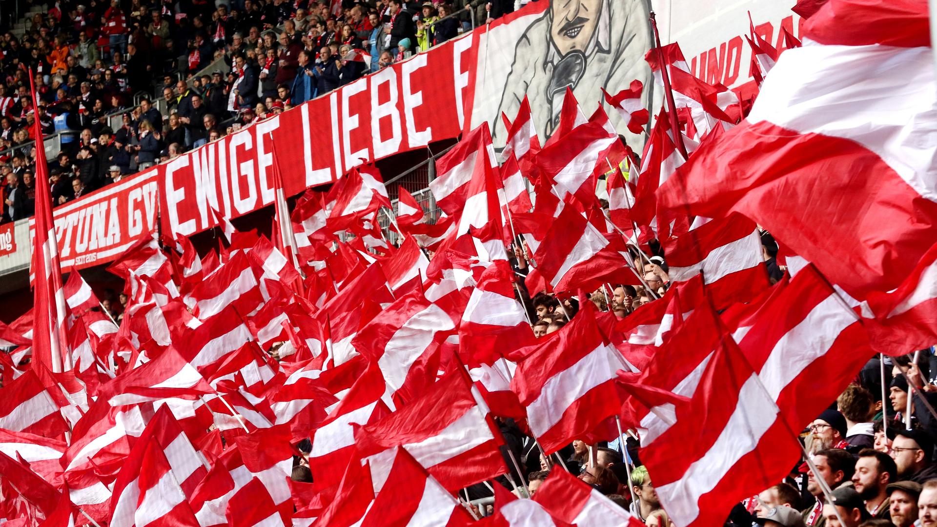Fans von Fortuna Düsseldorf schwenken viele rot-weiße Fahnen. Fans von Fortuna Düsseldorf schwenken viele rot-weiße Fahnen.