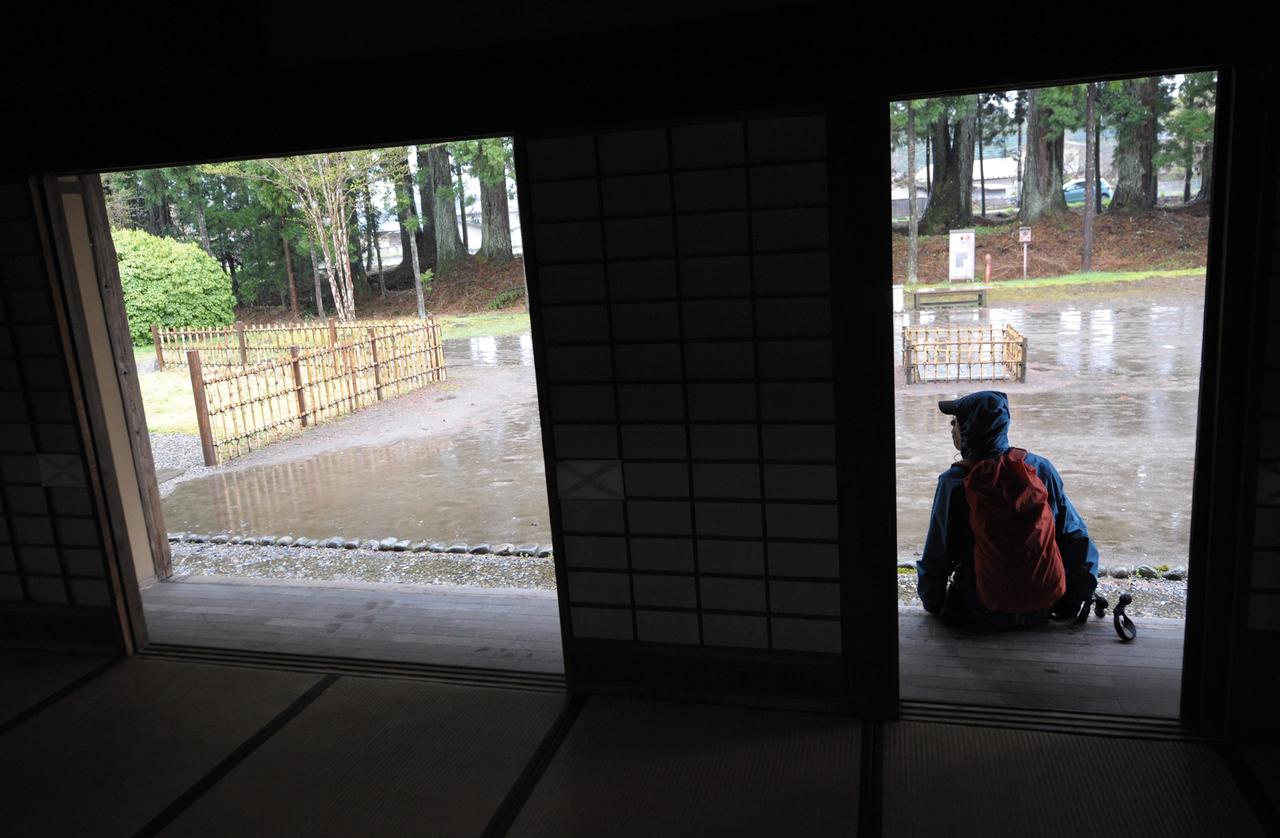 Ein junger Mann in Regenkleidung hat sich wegen Regens untergestellt