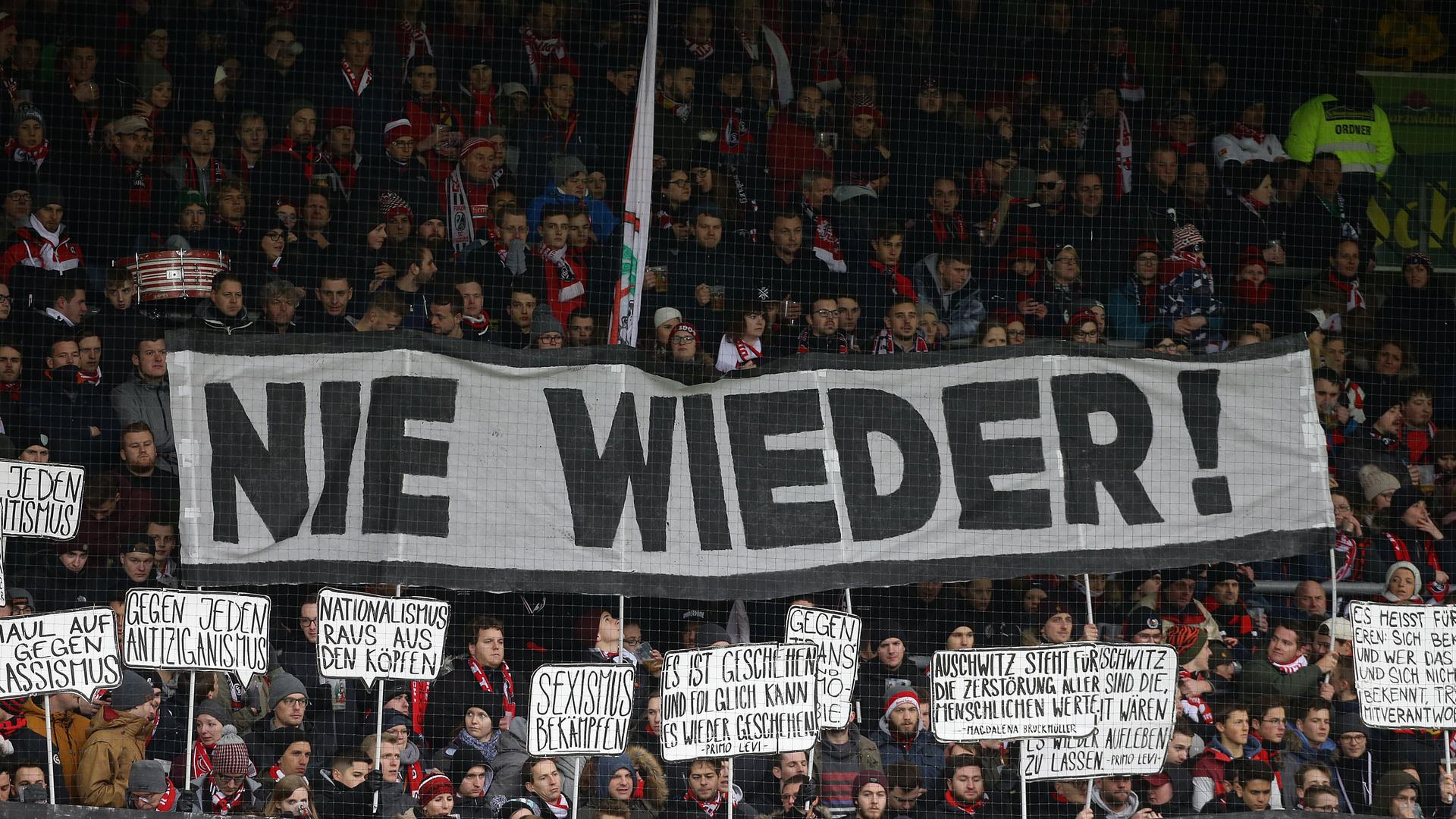 Fans des SC Freiburg beim Fußball-Bundesligaspiel gegen 1899 Hoffenheim mit dem Spruchband "Nie Wieder" anlässlich des Erinnerungstages im deutschen Fußball Fans des SC Freiburg beim Fußball-Bundesligaspiel gegen 1899 Hoffenheim mit dem Spruchband "Nie Wieder" anlässlich des Erinnerungstages im deutschen Fußball