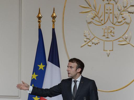 Der französische Präsident Macron hält eine Rede und zeigt mit seinem Arm nach links.
