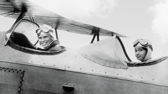 Ein Mann und eine Frau sitzen in einem Segelflugzeug alten Typs.