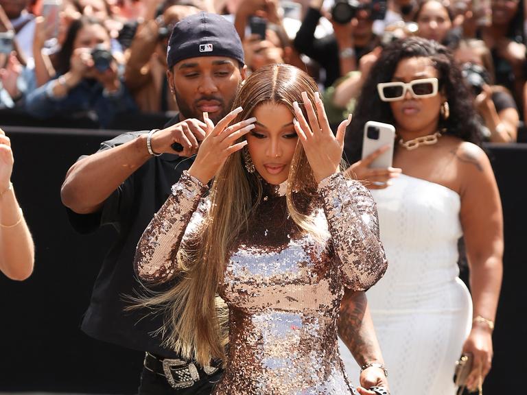 Cardi B tritt bei der Pariser Fashion Week auf. Im Hintergrund wird sie von mehreren Menschen mit der Handykamera abgelichtet. 