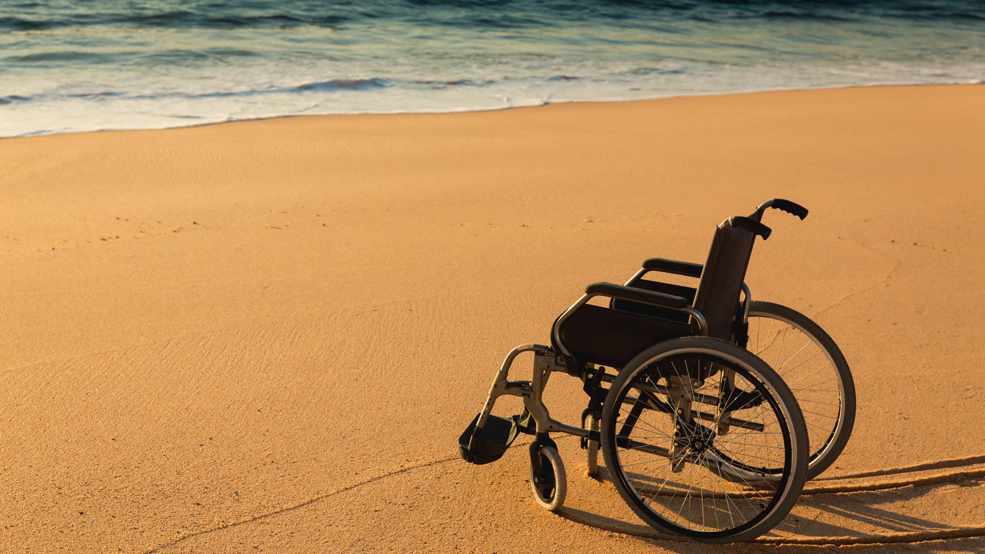 Verliert ein eingeschränktes Leben seinen Wert? Zu sehen: Ein Rollstuhl an einem Sandstrand am Meer. Verliert ein eingeschränktes Leben seinen Wert? Zu sehen: Ein Rollstuhl an einem Sandstrand am Meer.